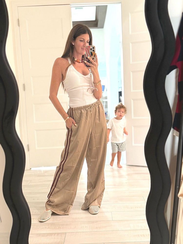 Donna wearing a white tank and tan track pants